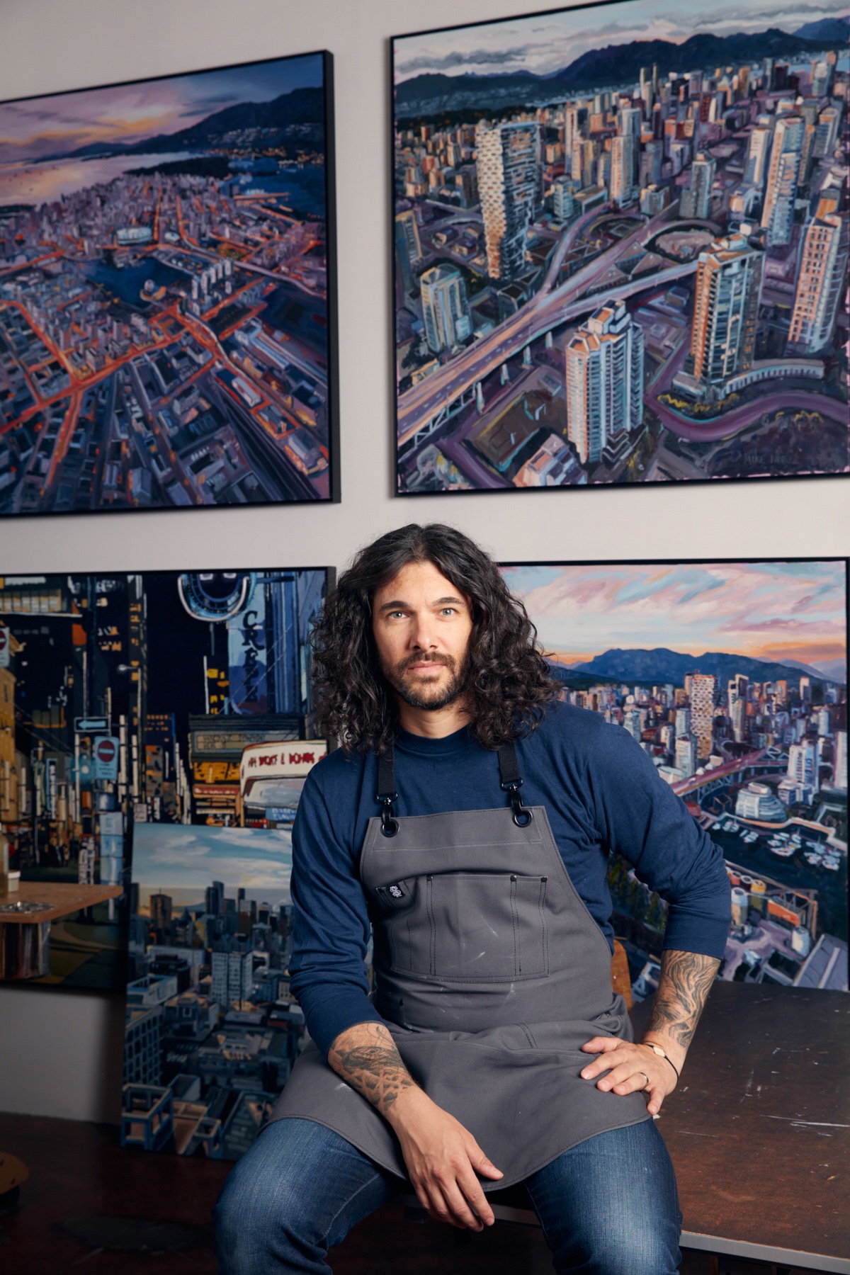  An artist sitting in front of various works of art.